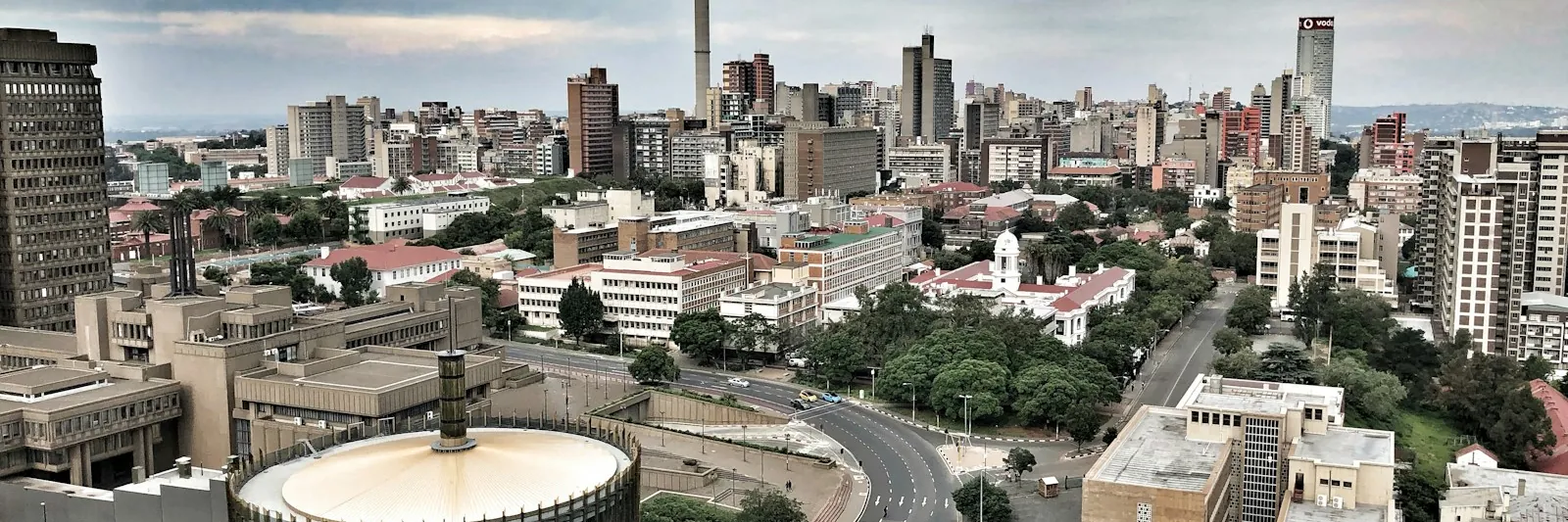 Elevated daytime view over the Johannesburg CBD with the Hillbrow Tower on the skyline, arterial roads and civic buildings in the foreground, dramatic cloud cov