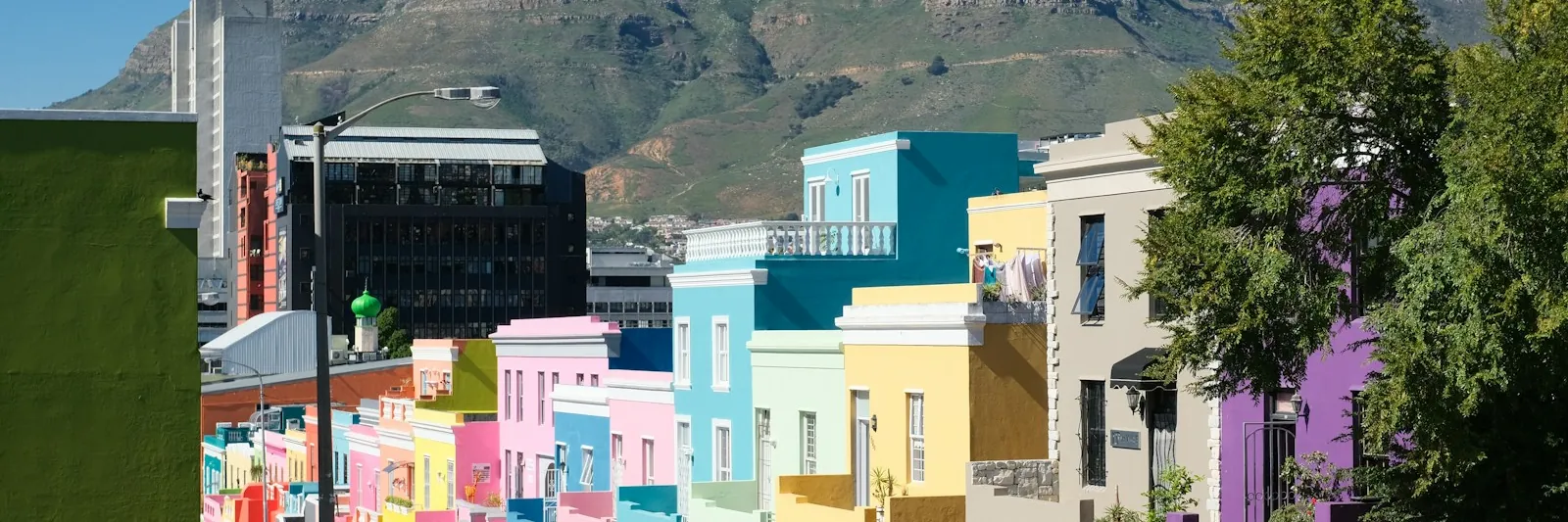 Brightly painted Bo-Kaap houses in Cape Town rising toward a mountain ridge