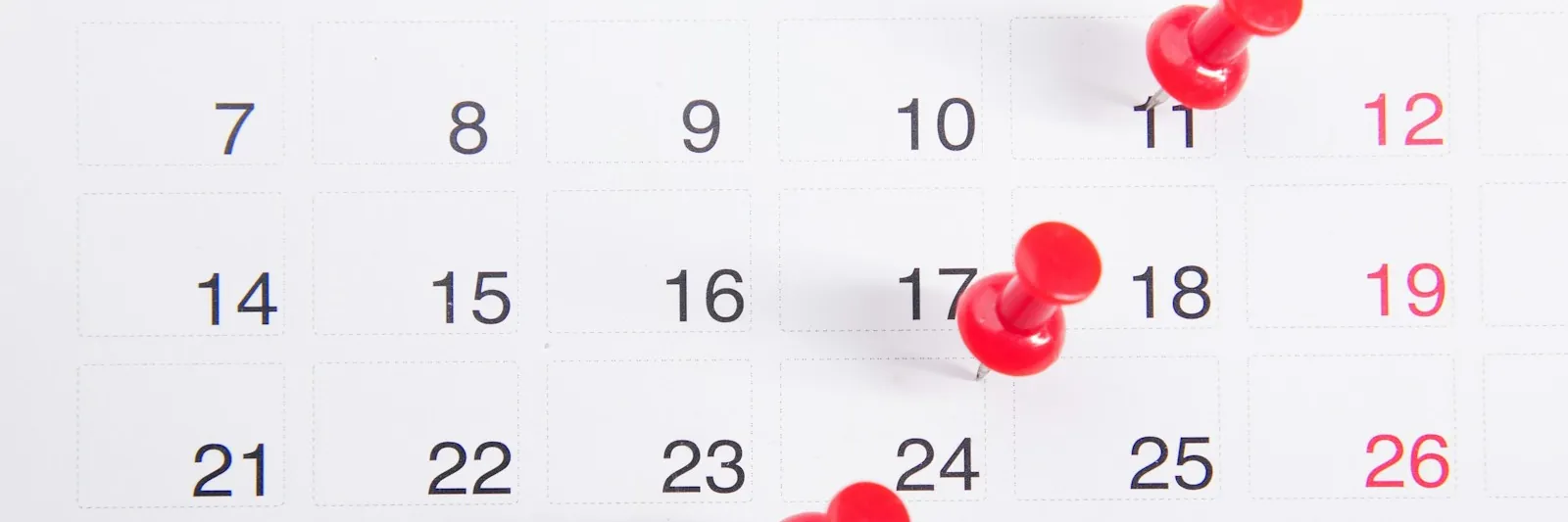 A blank monthly calendar grid with red push pins and a date circled in red marker